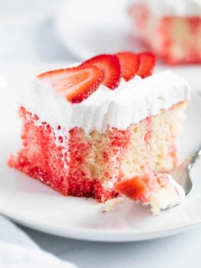A slice of poke cake with sliced strawberries on top.